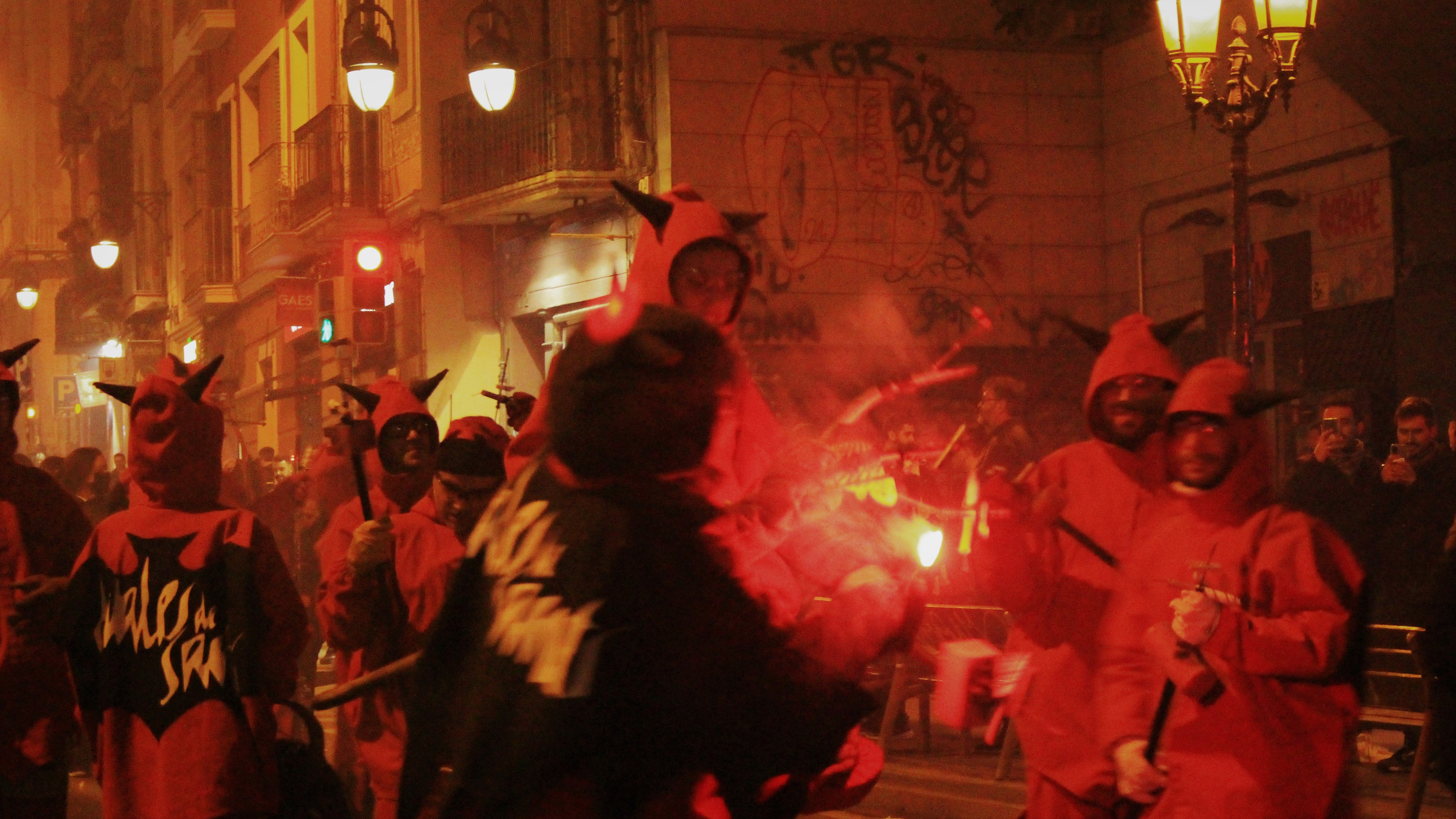 Photo of diables in the dark gathering around a fire source about to lit up their cartridges.