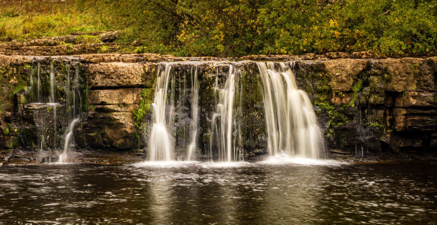 Up close photo of a small waterfall in a very green and natural scenario