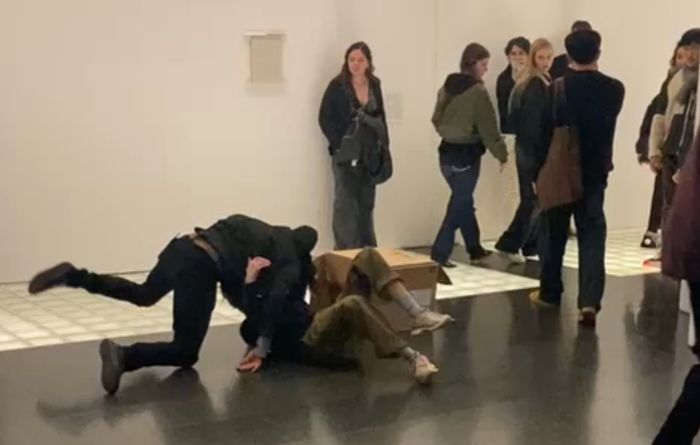 Photo of me engaged in contact improvisation and rolling over one of the performers as our mock fight for a cardboard box ends continues after we both fall
