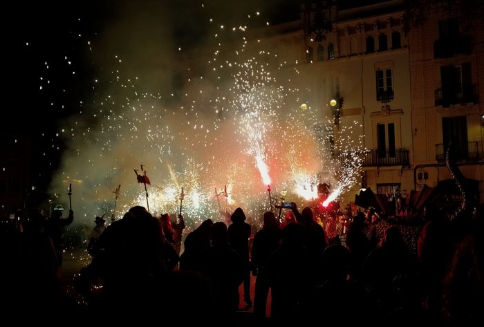 "Photo of the central plaza of GrÃ cia neighbourhood during the final act of the correfoc. There are dragons, and fire, and lightning sparkles shooting up the height of the 4 story buildings of the plaza